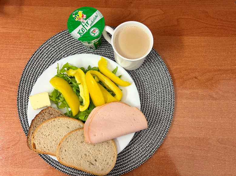 Na zdjęciu: Kefir 2% tł., Chleb mieszany pszenno-żytni, Chleb Graham, Masło extra 82%, Filet zapiekany drobiowy, Kawa zbożowa z mlekiem, Papryka świeża, Rukola